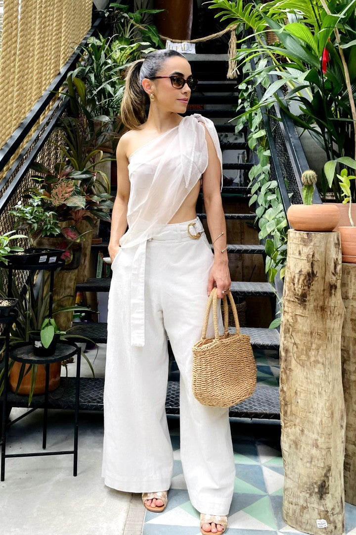 Mulher com look elegante vestindo calça pantalona alfaiataria de linho cru e blusa transparente