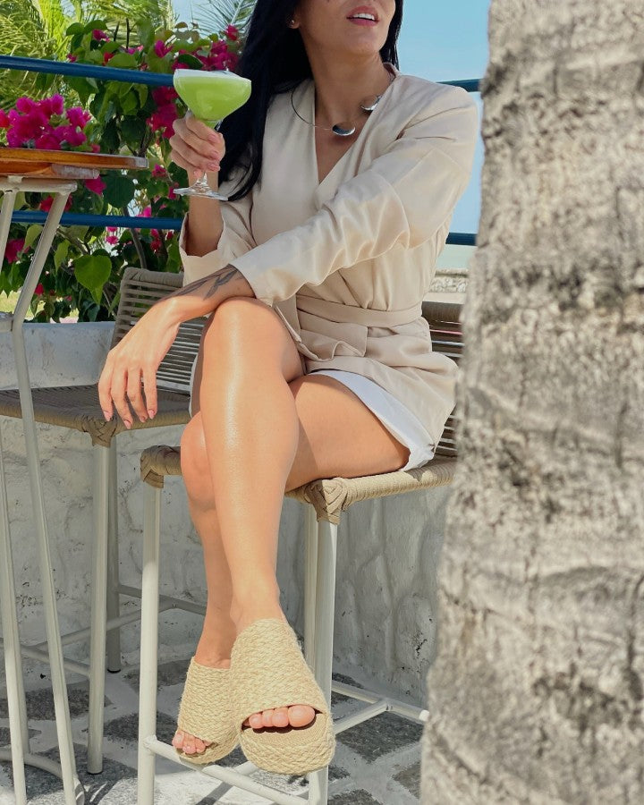 Modelo sentada vestindo blazer nude, bermuda branca e Sandalia Feminina Flatform de Fibra Natural.