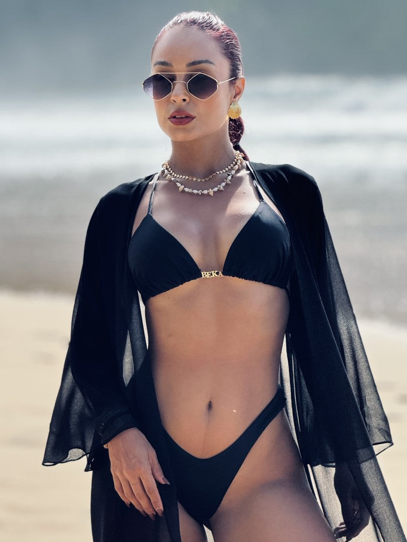 Mulher em praia vestindo um top biquini cortininha preto personalizado e calcinha biquini asa delta preto.