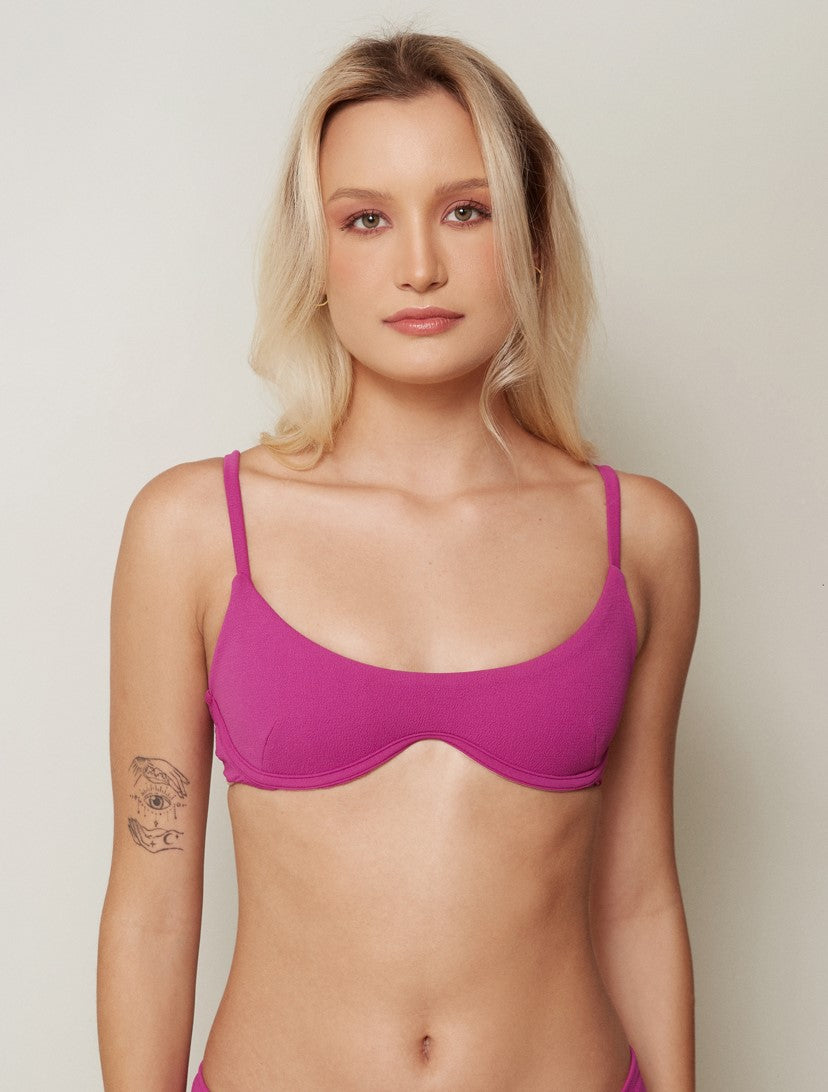 Modelo veste top biquíni meia taça rosa com aro.