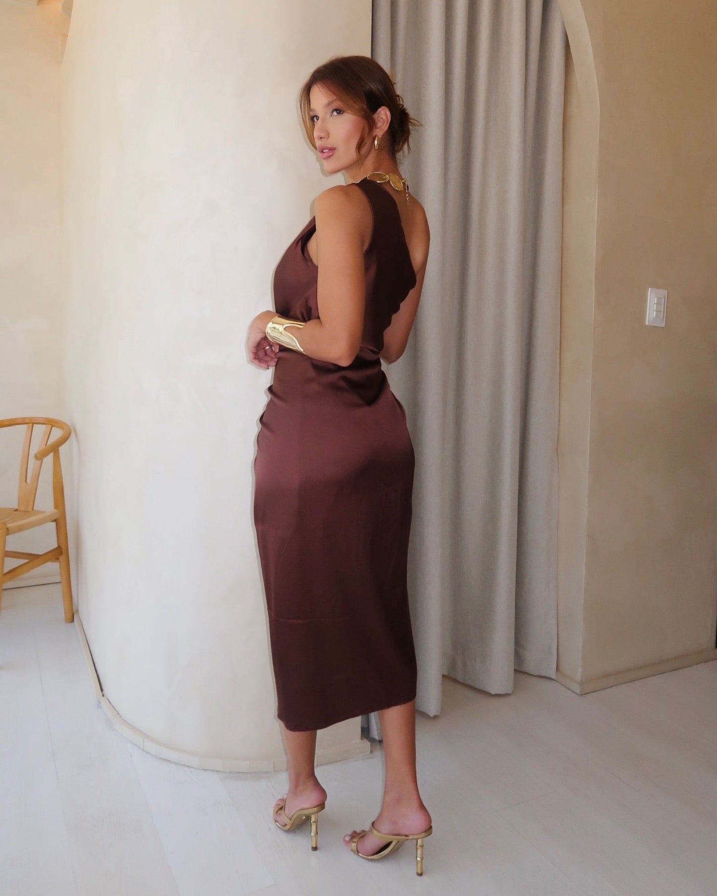 Modelo de costas usando vestido pareô midi marrom acetinado.