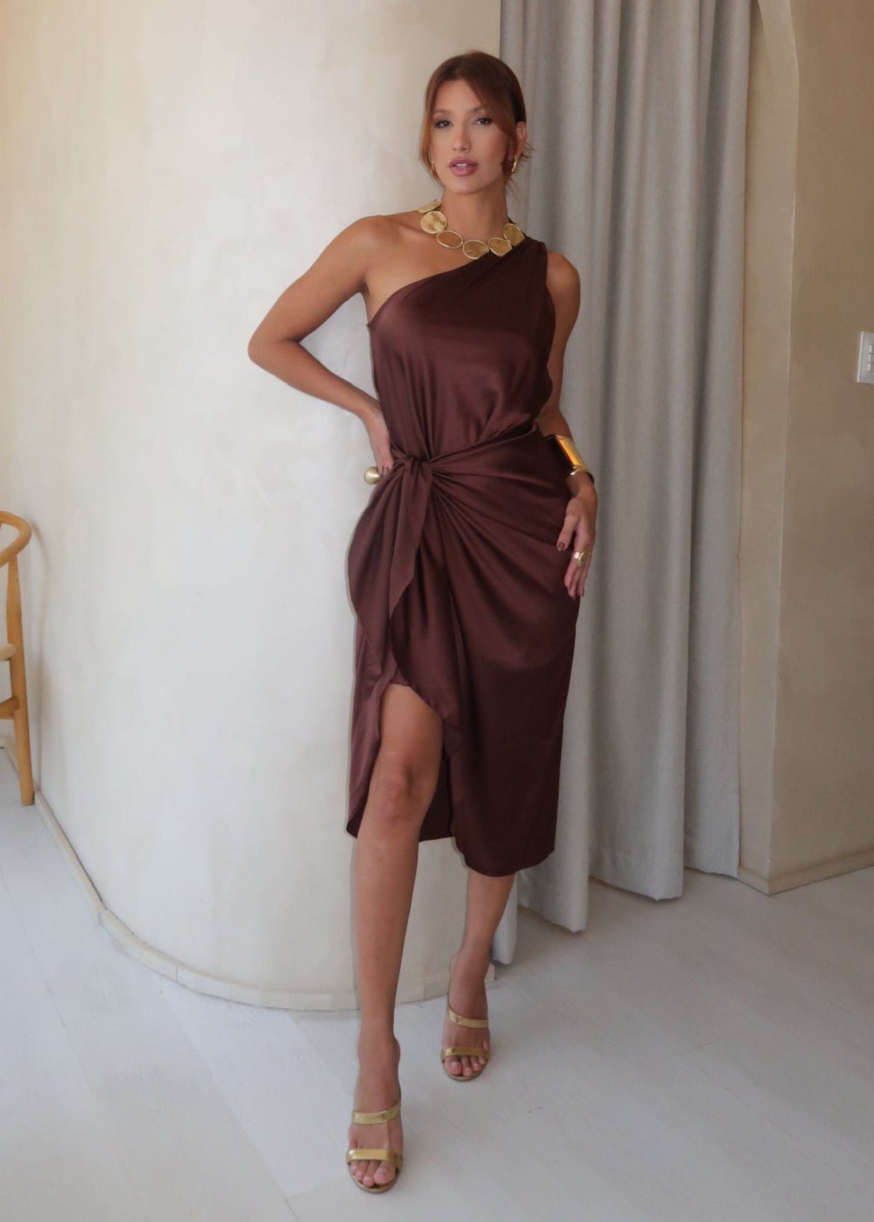 Modelo com look elegante, usando vestido marrom midi.