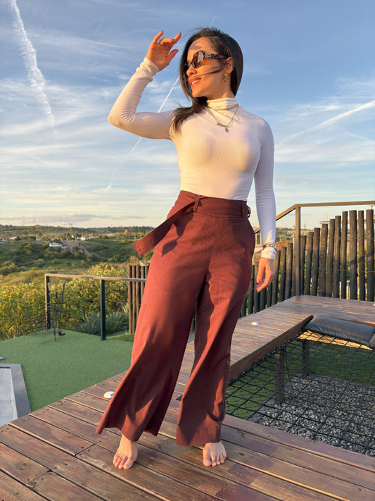 Modelo feminino vestindo calça pantalona marrom escuro e camisa branca de manga longa