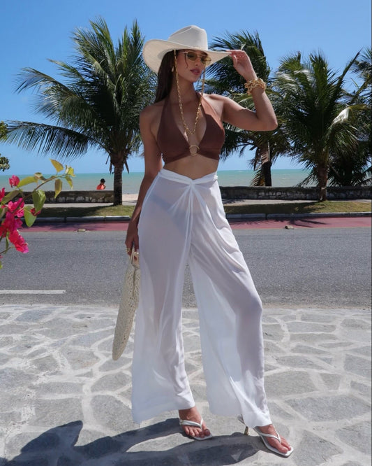 Maria veste calca pantalona branca  transparente elegante e top biquini marrom com argola dourada.